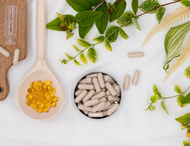 A table topped with spoons and pills next to plants.